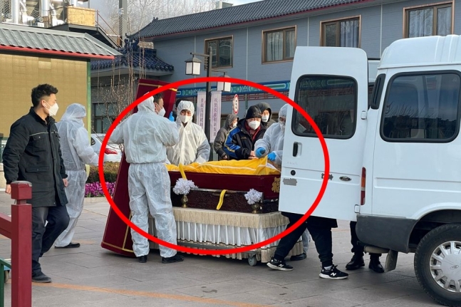 중국 수도 베이징에서 보호복을 입은 장례업체 관계자들이 장례식장에서 시신을 옮기고 있다. 2022. 12. 17 로이터 연합뉴스