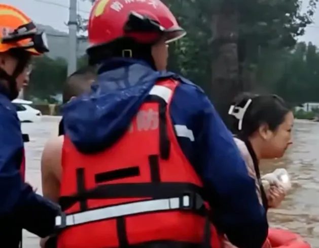 thumbnail - 남편의 요청에 따라 구명 튜브를 몸에 끼운 아내가 소방대원의 도움을 받아 구조되고 있다.