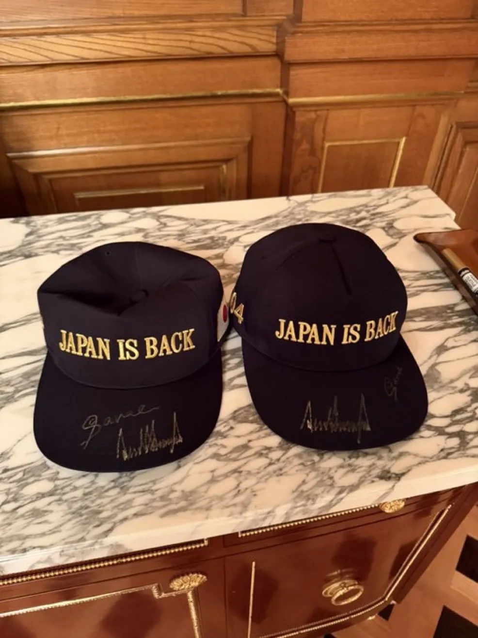 thumbnail - 백악관이 28일(현지시간) 공식 엑스(X·옛 트위터) 계정에 게시한 사진. 도널드 트럼프 미국 대통령과 다카이치 사나에 일본 총리가 도쿄 정상회담을 마친 뒤 함께 서명한 모자 두 개가 놓여 있다. 모자에는 아베 신조 전 총리의 구호였던 ‘재팬 이스 백(JAPAN IS BACK·일본이 돌아왔다)’ 문구가 금색으로 새겨져 있다. AFP 연합뉴스