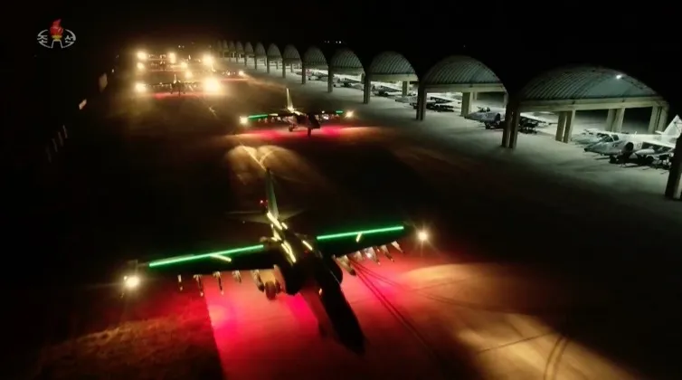 thumbnail - 북한 공군 수호이(Su)-25 공격기들이 야간 이륙 준비를 하고 있다. 기체 날개에는 녹색·적색 조명등이 점등돼 있으며, 격납고에는 다수의 전투기들이 대기 중이다. 2025년 11월 28일, 평안남도 순천비행장. 출처=조선중앙TV