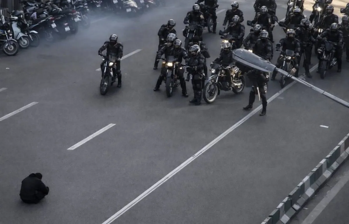 thumbnail - 이란 테헤란 시위 현장에서 무장한 경찰 오토바이 부대 앞 도로에 한 시위자가 홀로 앉아 있다. 해당 장면은 최근 이란 전역으로 확산된 시위 국면 속에서 상징적 이미지로 주목받고 있다. 엑스 캡처