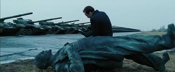 영화 로드오브워에서 무너진 레닌 동상을 깔고 앉아 무기 거래를 위해 계산기를 두드리고 있는 유리 올로프