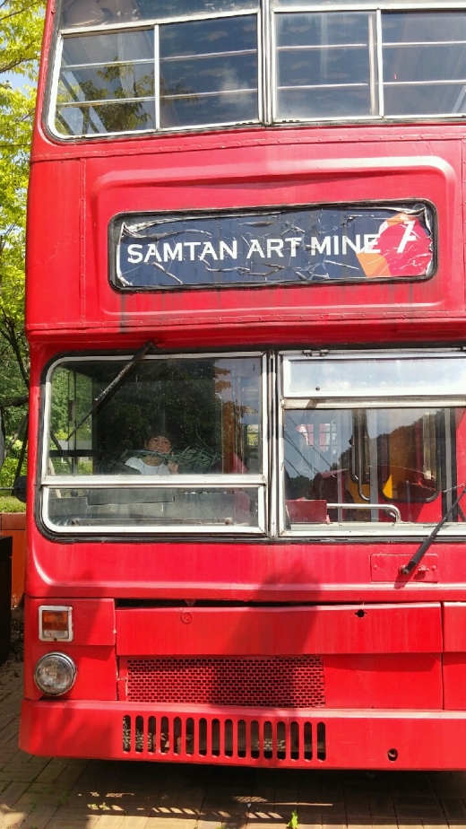 한 어린이가 2층 버스 운전석에 앉아 즐거워하고 있다.