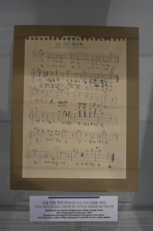 기록관에 전시된 필사본 ‘임을 위한 행진곡’ 악보. 2016년 5·18 기념 행사에서 제창과 합창의 방식 차이로 인해 한동안 뜨거운 논란의 대상이 된 노래이다. 합창(合唱)과 제창(齊唱)은 참석자가 같이 부른다는 점에서 큰 차이는 없다. 그러나 합창의 경우 합창단이 있어 참석자들은 안 불러도 무방하지만, 제창의 경우 참석자 전원이 부르는 경우이다. 애국가는