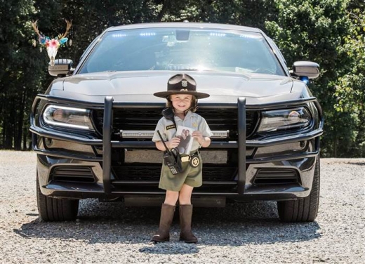 탈리야가 할아버지의 보안관 차 앞에서 아빠 사진을 들고 3살 기념사진을 찍고 있다. 모자와 배지, 장화에 무전기까지 갖춘 탈리야의 모습이 앙증맞다. (사진=매리 리)