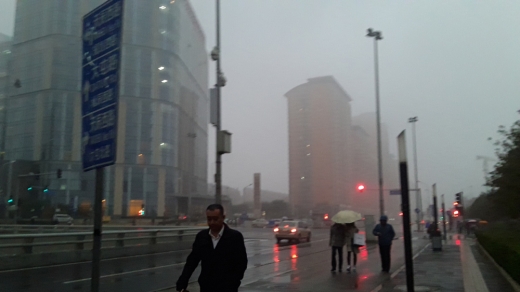 지난 3일 오후 베이징 시내 풍경. 비가 내리는 속에서도 미세먼지가 가득한 상황이다. 마스크도 쓰지 않은 채 걸어가는 시민들이 눈에 띈다.
