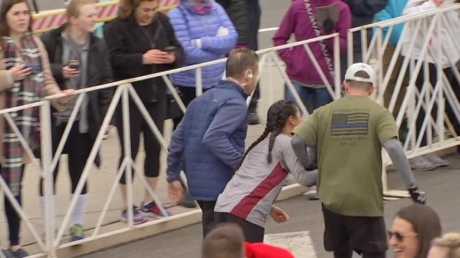 두 명의 남성이 여성의 양팔을 붙들고 마라톤을 이어가려 하고 있다. (사진=더썬)