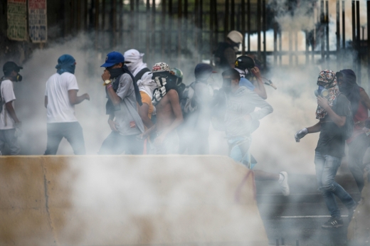 24일(현지시간) 베네수엘라 카라카스에서 열린 반정부시위에서 경찰들이 쏜 뿌연 최루탄 연기 속에서 시위대들이 고통스러워하고 있다. (EPA/연합뉴스)