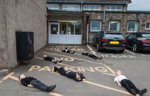 파킹 금지구역에 버젓이 차를 대는 학부모들에게 주차를 하지 말라고 몸의 언어로 표현하고 있는 중. (사진=데일리메일 캡쳐)