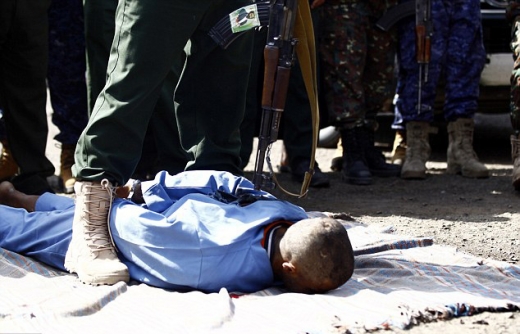 엎드려 있는 죄수에게 총을 겨누고 있다.