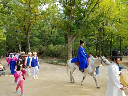 혼례가 끝나고 신랑과 신부가 민속촌 안을 돌고 있다
