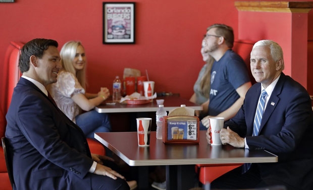 20일(현지시간) 미국 플로리다주 올랜도의 버거 레스토랑에서 테이블에 앉은 마이크 펜스 미 부통령(오른쪽)과 론 디샌티스 주지사./사진=AP 연합뉴스
