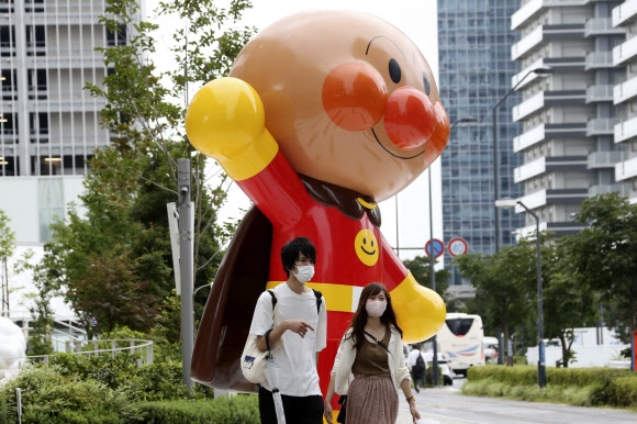 일본 도쿄 인근 요코호마에서 한 커플이 코로나19 예방 마스크를 쓴 채 만화 캐릭터 호빵맨 모형 앞을 지나고 있다 (사진=AP연합뉴스) 
