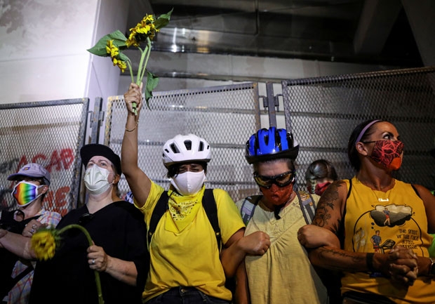 19일(현지시간) 포틀랜드주 연방법원 앞에서 엄마방패 회원 등이 스크럼을 짜고 연방요원 앞을 가로막았다./사진=로이터 연합뉴스