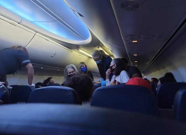 코로나19 감염사실을 숨긴 채 탑승했다가 비행기에서 의식을 잃은 남성을 돕기 위해 승무원과 승객들이 나선 모습