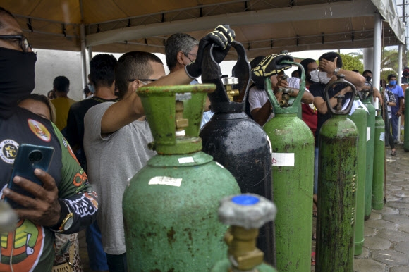 브라질 현지시간으로 19일, 코로나19 환자를 가족으로 둔 사람들이 치료에 필요한 산소를 얻기 위해 산소탱크를 들고 직접 업체 앞에 줄을 선 모습. 사진 AFP 연합뉴스