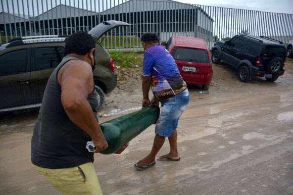 브라질 현지시간으로 19일, 코로나19 환자를 가족으로 둔 사람들이 치료에 필요한 산소를 얻은 뒤 직접 이를 옮기는 모습. 사진 AFP 연합뉴스