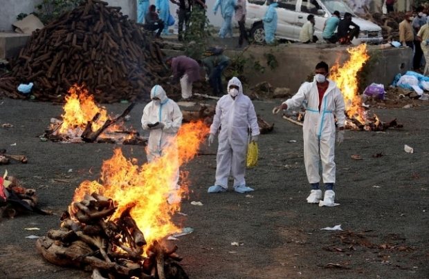인도의 화장장이 몰려드는 시신으로 포화상태에 이르렀다. 방역복을 입은 직원들이 화장용 장작더미 사이를 지나가는 모습. EPA 연합뉴스