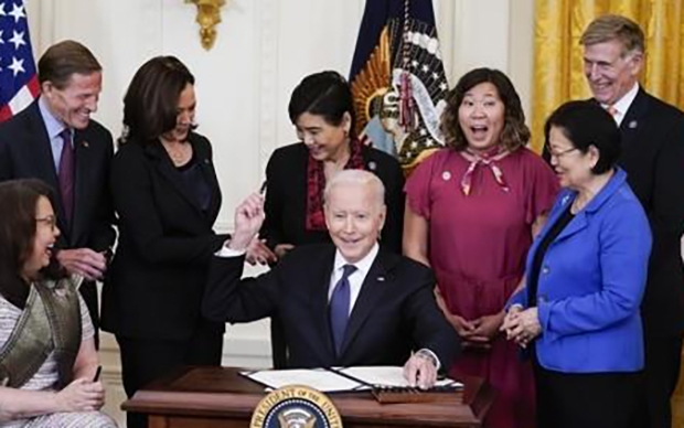 20일(현지시간) 미국 워싱턴DC 백악관 이스트룸에서 조 바이든 대통령(가운데)이 민주당 소속 상·하원 의원과 카멀라 해리스 부통령(왼쪽·3번째)이 지켜보는 가운데 아시아계 증오범죄 방지법안에 서명한 후 사용한 펜을 참석자에게 건네주고 있다. 이 법안은 신종 코로나바이러스 감염증(코로나19) 대유행 이후 아시아계 미국인을 대상으로 한 증오범죄가 늘어나자 지난 3월에 발의됐으며, 최근 상·하원을 통과했다./AP연합뉴스