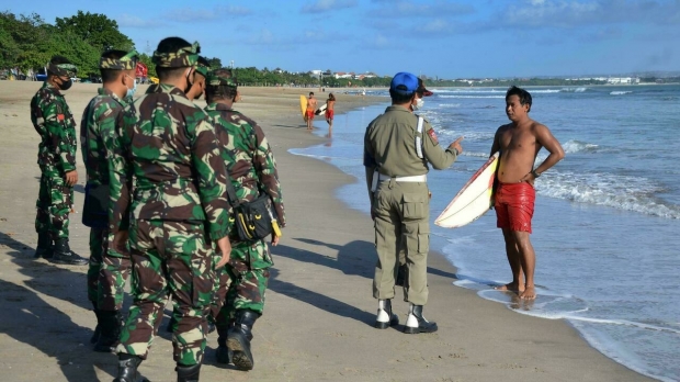 지난 4일 인도네시아 발리의 한 해변에서 현지 경찰과 군인이 순찰 중에 관광객에게 마스크 착용을 지시하는 모습.(사진=AFP 연합뉴스)
