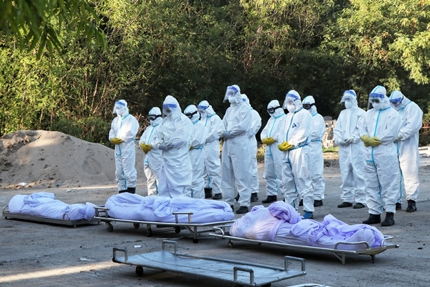 14일 미얀마 만달레이의 한 공동묘지 장례식에서 개인보호장비를 착용한 자원봉사자들이 코로나19 사망자들을 위해 기도하고 있다./AP연합뉴스