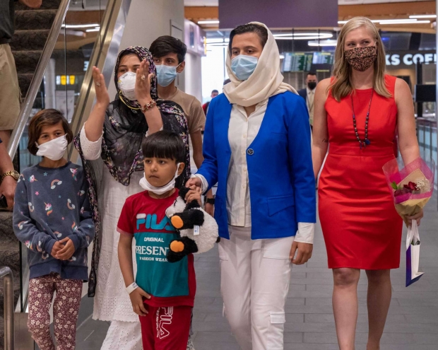 무늬가 들어간 검은색 스카프를 쓴 수니타와 그녀의 네 자녀의 모습. 이들 가족의 오른쪽에는 빨간색 원피스 차림의 세라 라우리 변호사가 서 있다.