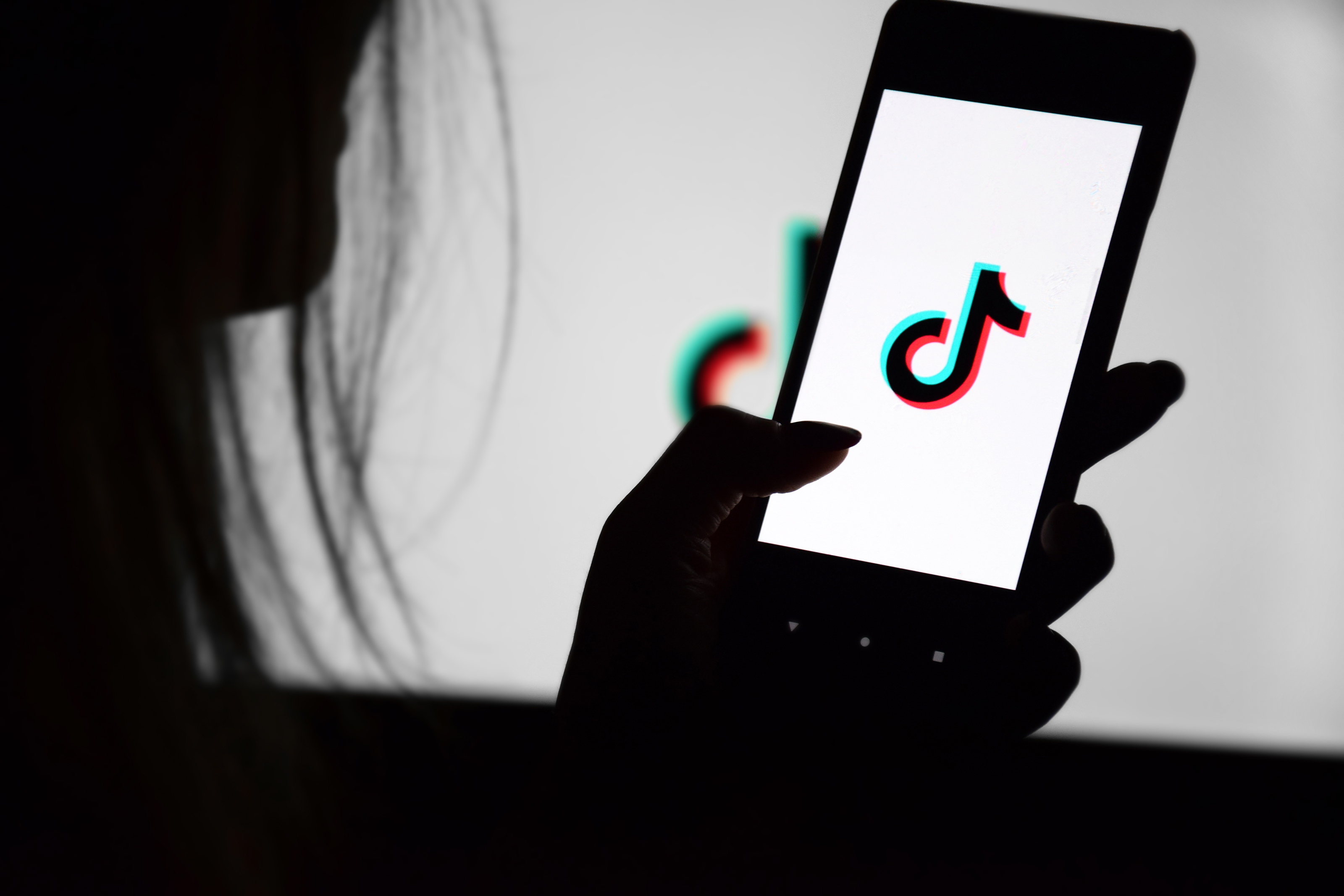 A phone with a Tik Tok screen in the hands of a young girl against the background of a monitor. Selective focus. 자료사진. 123rf A phone with a Tik Tok screen in the hands of a young girl against the background of a monitor. Selective focus. 자료사진. 123rf