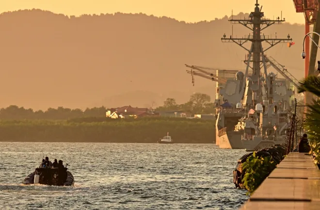 트리니다드토바고 해안경비대 순찰정이 2025년 10월 27일(현지시간) 포트오브스페인 항에 정박한 미국 구축함 그래블리함  주변 해역을 경계하고 있다. 트리니다드토바고의 캄라 퍼사드-비세서르 총리는 베네수엘라가 미국 군함 입항을 이유로 공동 가스 개발 사업 중단을 위협하자 이를 일축했다. AFP 연합뉴스