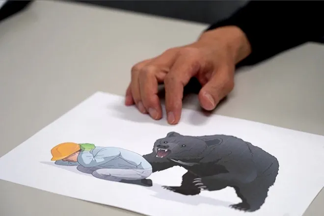 일본 아키타대학병원에서 나카에 하지메 응급·중증의학 교수가 곰 공격 시 대응 요령을 설명하는 안전 일러스트를 보여주고 있다. 일본에서는 올해 4월 이후 곰 습격으로 사망자가 역대 최다인 13명에 이르렀으며, 곰이 학교·주택가·상점가까지 잇따라 출몰하고 있다. 2025년 10월 26일 촬영. AFP 연합뉴스