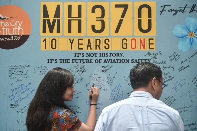 MH370 여객기 실종 10주년을 맞아 추모 글을 남기는 여성. AFP 연합뉴스 자료사진