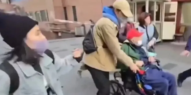 병원 밖에서 가족들이 102세 왕 씨가 탄 휠체어를 둘러싸고 이동을 시도하는 모습.