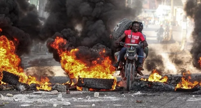 갱단들이 경찰을 저지하기 위해 타이어에 불을 지른 가운데 주민들이 불에 그슬린  타이어를 가져가고 있다. 에우로파프레스 캡처
