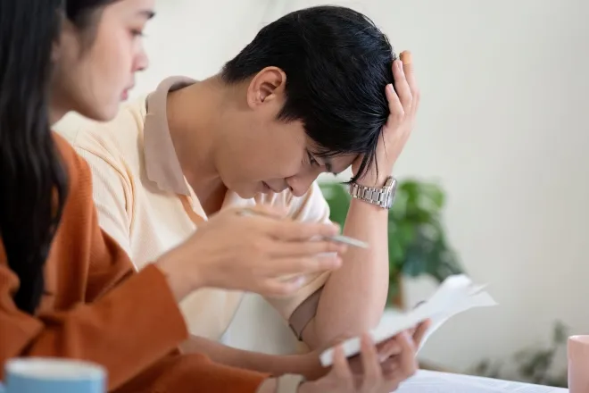 한 커플이 집에서 생활비 관련 서류를 살펴보며 고민하고 있다. 123RF