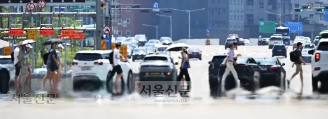 서울 한낮 기온이 35도까지 치솟으며 폭염이 이어진 12일 영등포구 여의대로에서 시민들이 아지랑이가 피어오르는 도로 위 횡단보도를 건너고 있다. 북태평양고기압과 티베트고기압이 우리나라를 겹겹이 덮는 ‘이중 고기압 이불’ 현상 탓에 극심한 더위가 찾아왔다. 홍윤기 기자