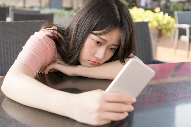 스마트폰을 바라보며 생각에 잠긴 여성. 중국이 AI 동반자 서비스의 정서적 의존을 막기 위한 규제를 시행하면서 일부 이용자들은 가상 연인과 강제로 헤어진 듯한 상실감을 호소하고 있다. 123rf